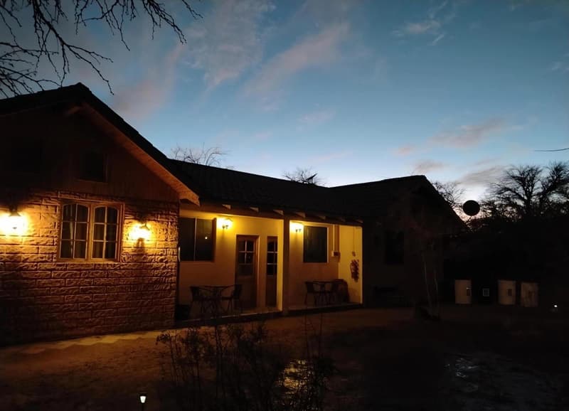 Cabañas al atardecer, con un volcán nevado al fondo y el cielo anaranjado.